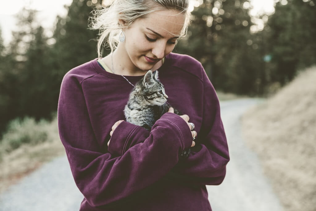 Young woman cuddling a cat in her  arms and showing us a lovable woman.