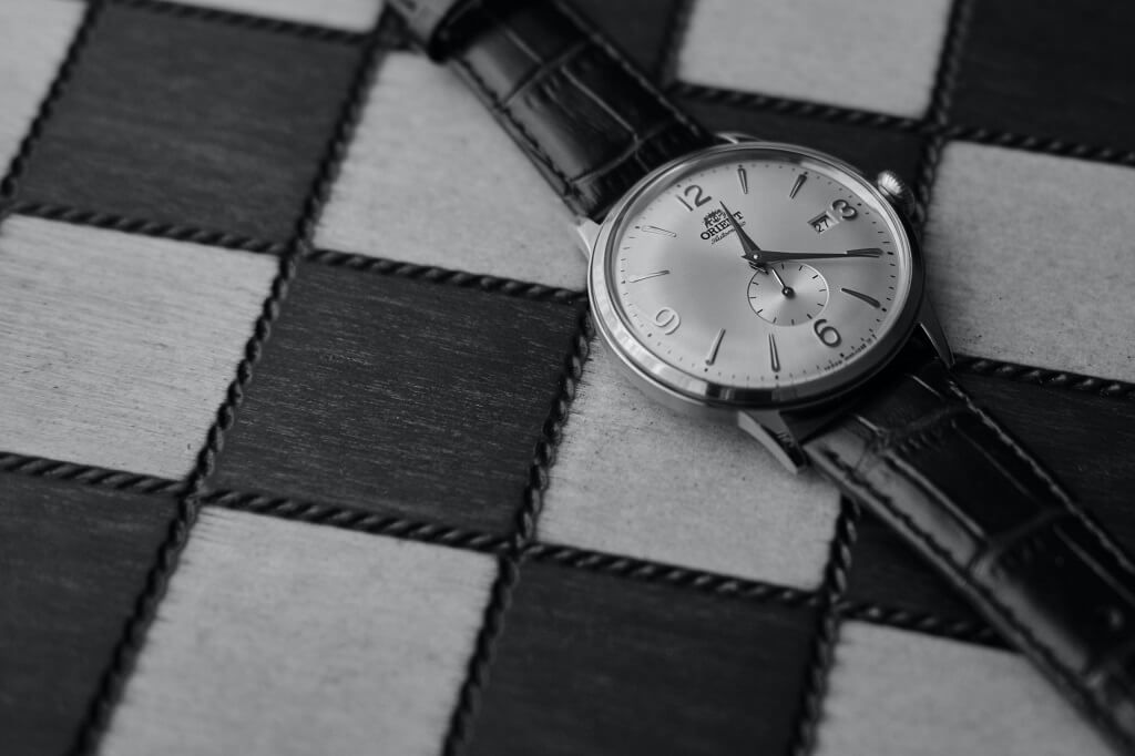 Think about what time is it in life as you look at a black and white picture of a wrist watch on a checkered  background.