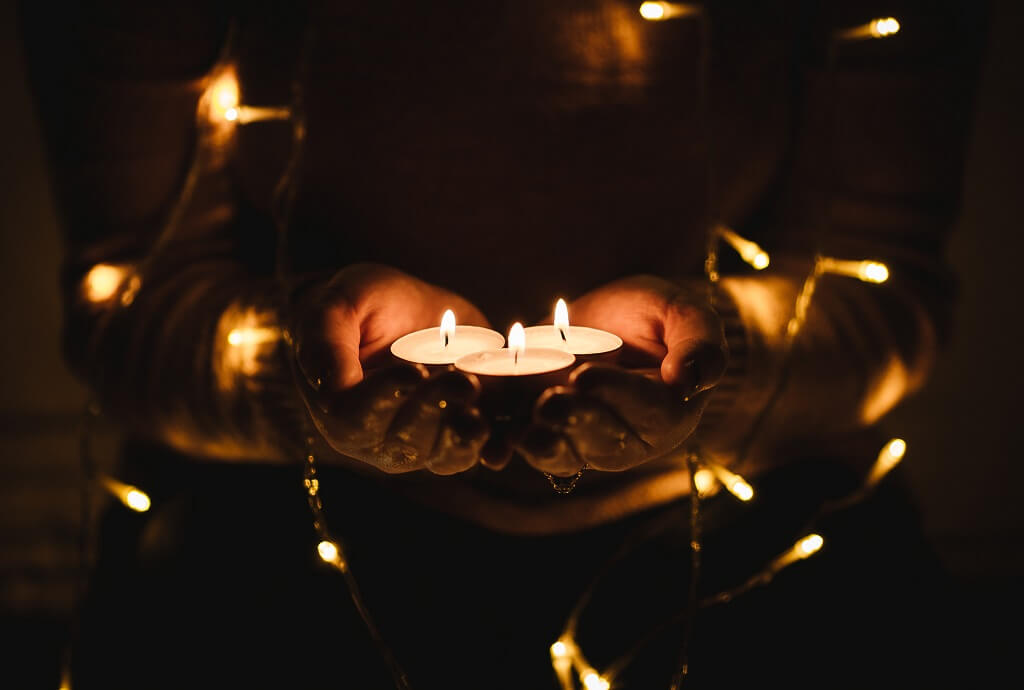 Two hands holding votive candles in the dark, representing the joy of building a real life.