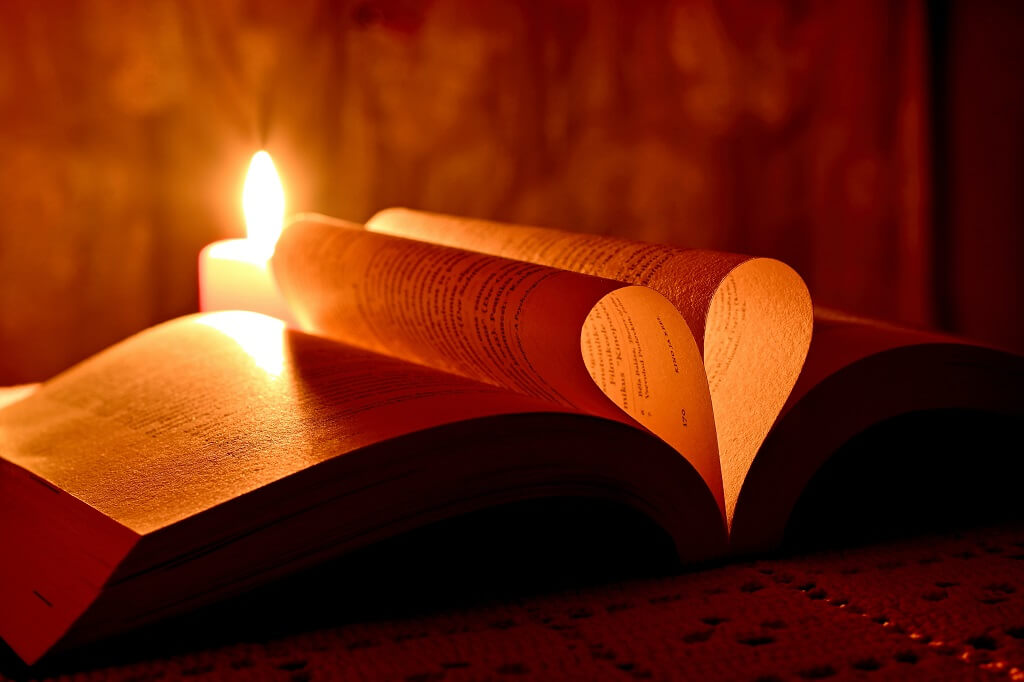 The picture shows written pages formed in a heart shape and glowing from the light of a candle reminding us that we are blessed and should be grateful. 