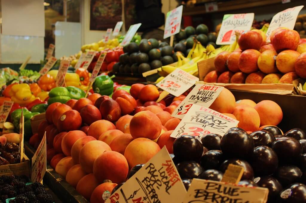 The photo shows how great it is to build a healthy relationship with food. We see beautiful peaches, plums, berries and other fruits on display in a farmer's market. 