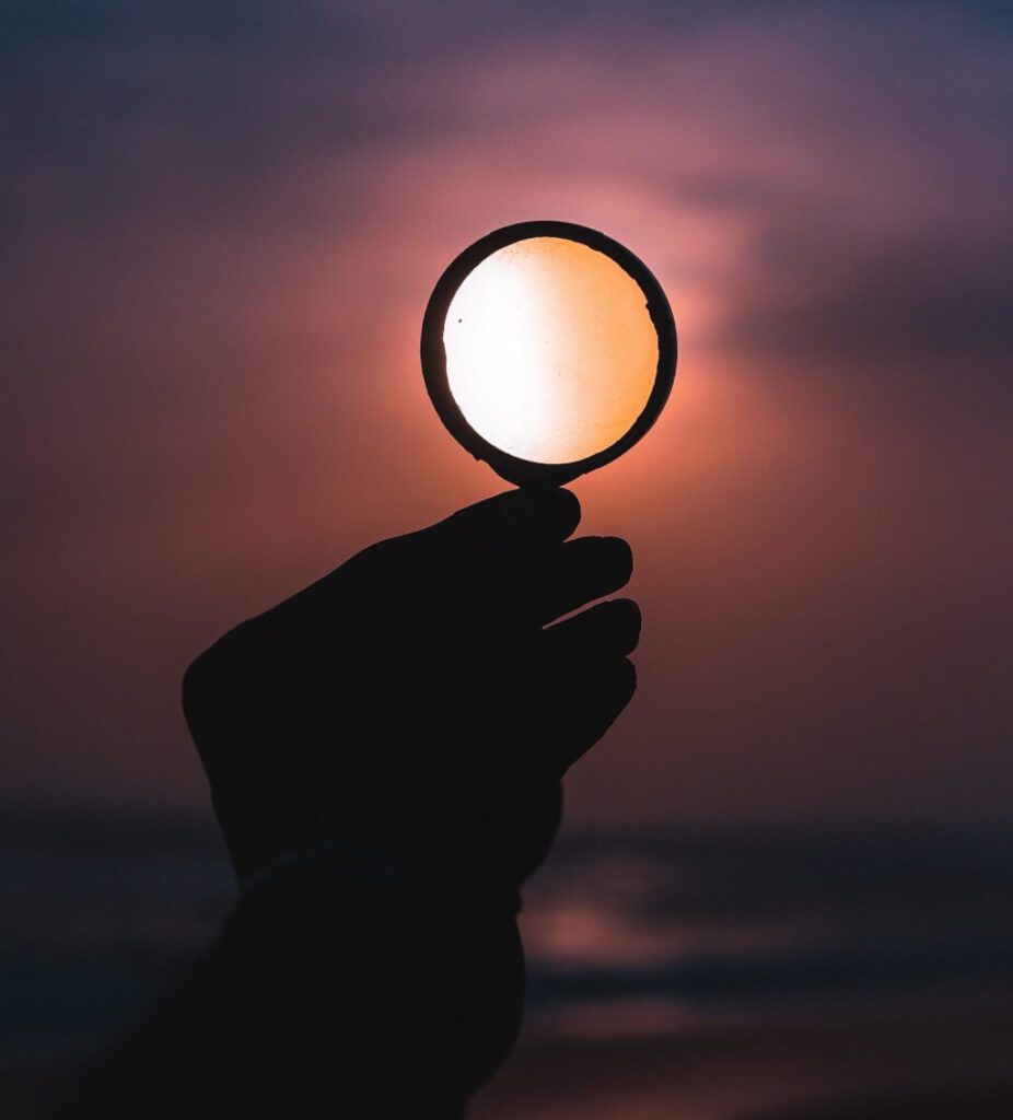 To solve a problem we see a photo showing the hand of a person holding up a magnifying glass against the sky, as bright light shines through the glass.